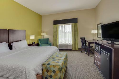 a hotel room with a bed and a flat screen tv at Hampton Inn Ozark in Ozark