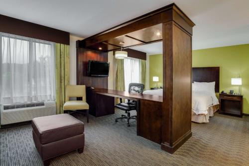 a hotel room with a bed and a desk and a bedroom at Hampton Inn Ozark in Ozark