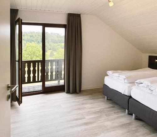 a bedroom with two beds and a large window at Ferienpark Rursee in Simmerath