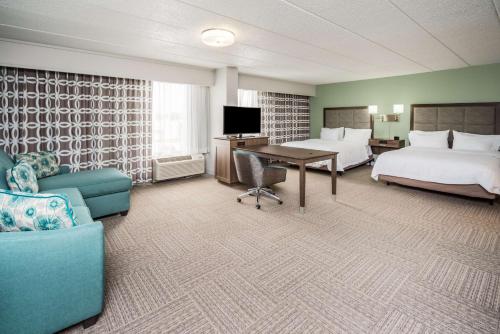 ドーバーにあるHampton Inn Doverのベッド2台、テーブル、ソファが備わるホテルルームです。