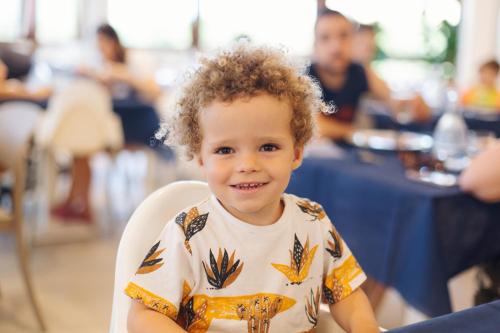 a young boy sitting in a chair smiling at the camera at Canado Club Family Village in Marina di Castagneto Carducci