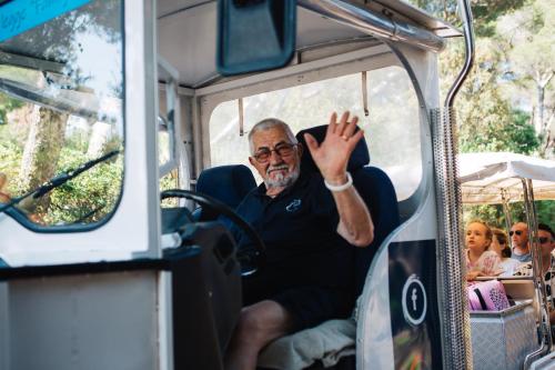 an older man waving from the back of a bus at Canado Club Family Village in Marina di Castagneto Carducci
