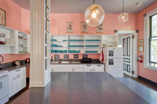 a kitchen with pink walls and white cabinets at HI Sacramento Hostel in Sacramento