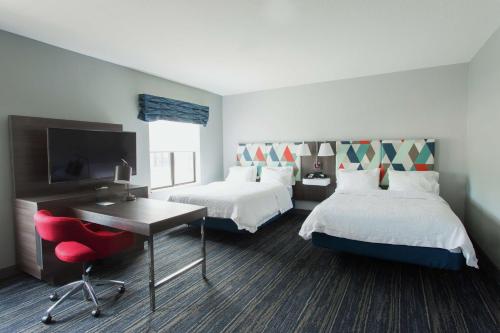 Habitación de hotel con 2 camas, escritorio y TV. en Hampton Inn & Suites Ankeny, en Ankeny
