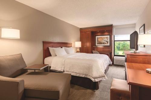 a hotel room with a bed and a chair at Hampton Inn Des Moines-Airport in Des Moines