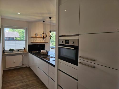 a kitchen with white cabinets and a black counter top at Ferienwohnung Messinger in Seebruck
