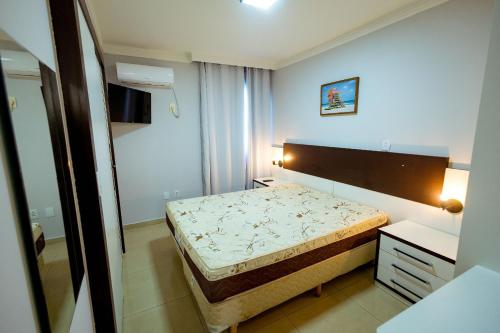 a small bedroom with a bed and a mirror at Thermas Paradise - Rio Quente- Duplex 3 Quartos com Hidromassagem in Rio Quente