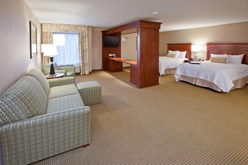 a hotel room with two beds and a couch at Hampton Inn Detroit/Auburn Hills-North in Auburn Hills