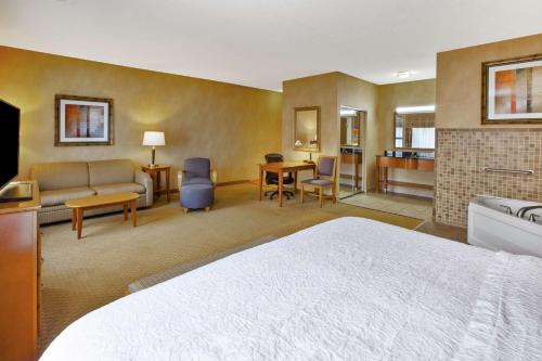 a hotel room with a bed and a living room at Hampton Inn Detroit - Shelby Township in Shelby