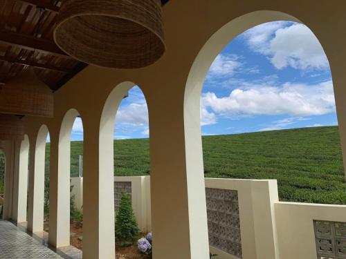 - une vue sur un champ verdoyant depuis un bâtiment avec des arches dans l'établissement Villa Mộc Châu Teahouse, à Mộc Châu
