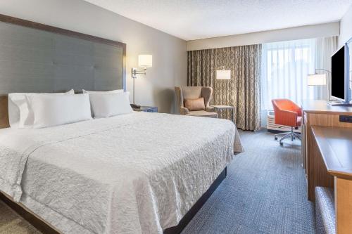 Hampton Inn Eau Claire في أو كلير: غرفه فندقيه سرير وتلفزيون