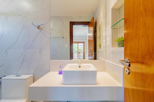 a white bathroom with a sink and a toilet at PF55 Ótima Casa 4 Suítes - Praia do Forte in Farol