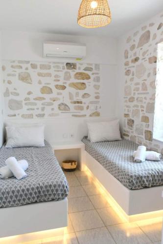 a bedroom with two beds and a stone wall at Sea View Stone House in Naousa