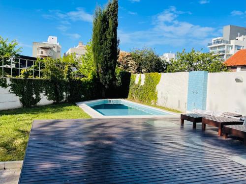 a swimming pool in a yard with two benches and a fence at Check and Home - San Lorenzo - 2 Huéspedes con Pileta y Cochera in Mar del Plata