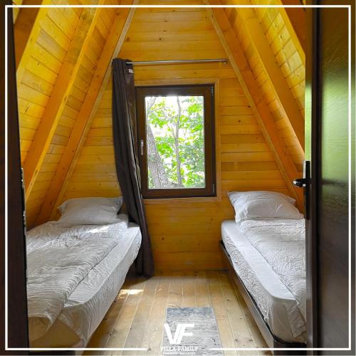 two beds in a wooden cabin with a window at Villa Family in Orllan