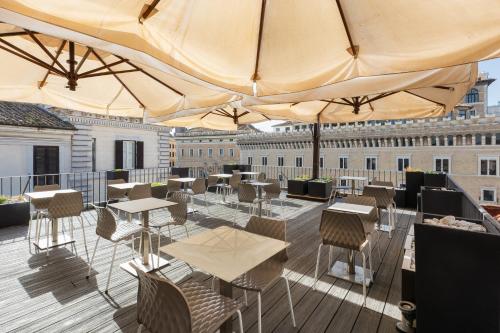 un patio all'ultimo piano con tavoli, sedie e ombrelloni di Hotel Castellino Roma a Roma