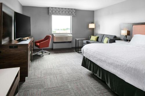 Hampton Inn & Suites West Bend في West Bend: غرفة فندقية بسرير وتلفزيون بشاشة مسطحة