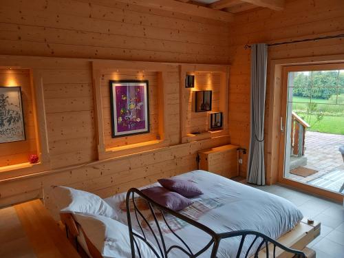 1 dormitorio con 1 cama en una cabaña de madera en Les Abeilles, en Prez-vers-Siviriez