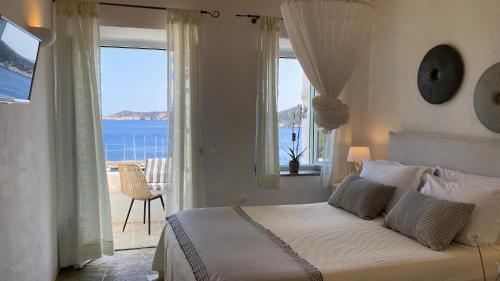 a bedroom with a bed with a view of the ocean at Niriedes Hotel in Platis Gialos