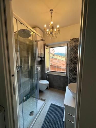 een badkamer met een douche, een toilet en een kroonluchter bij Delizioso bilocale Mottino23 in Lerici