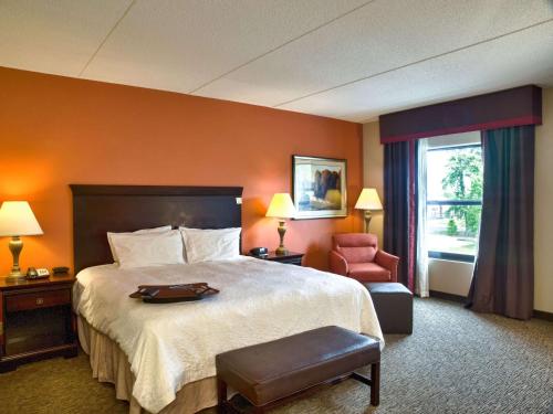 ein Hotelzimmer mit einem großen Bett und einem Stuhl in der Unterkunft Hampton Inn Spring Lake Fayetteville in Spring Lake