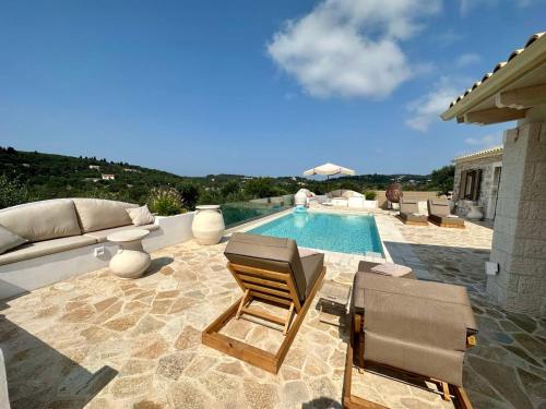 a swimming pool with two chairs and a couch next to at Villa Nikolas - Secluded and luxurious in Oziás