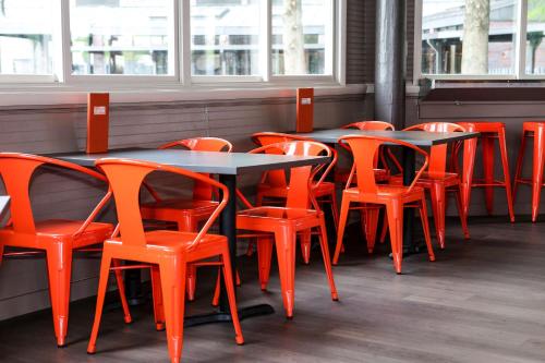a row of tables and orange chairs in a restaurant at Hampton Inn Frederick in Frederick