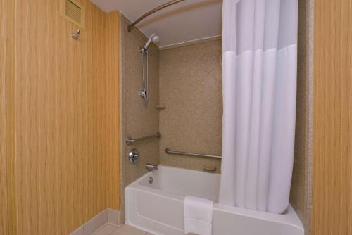 a bathroom with a shower with a white shower curtain at Hampton Inn Frederick in Frederick