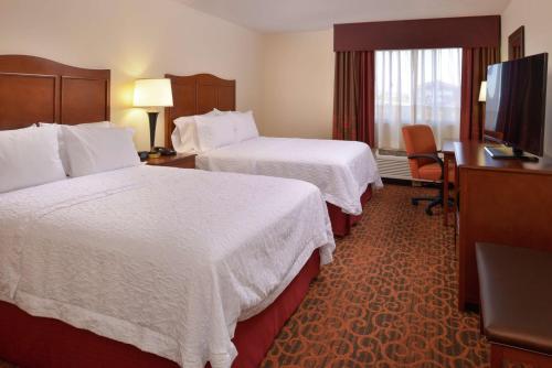 a hotel room with two beds and a flat screen tv at Hampton Inn Frederick in Frederick