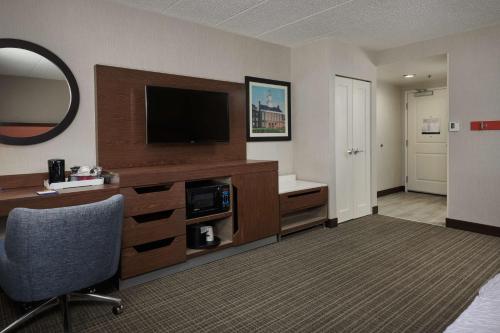 a hotel room with a television and a desk with a chair at Hampton Inn Fairfax City in Fairfax