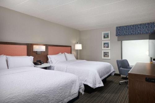 a hotel room with two beds and a chair at Hampton Inn Fairfax City in Fairfax