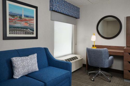 a living room with a blue couch and a mirror at Hampton Inn Fairfax City in Fairfax