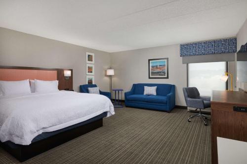 a hotel room with a bed and blue chairs at Hampton Inn Fairfax City in Fairfax