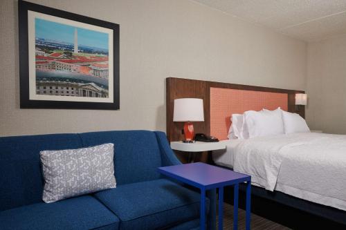 a hotel room with a bed and a blue couch at Hampton Inn Fairfax City in Fairfax