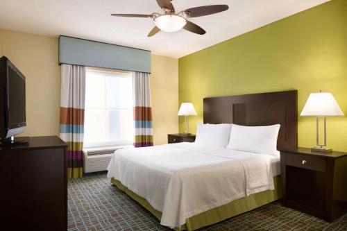 Homewood Suites Fort Myers Airport - FGCU في فورت مايرز: غرفة فندقية بسرير وتلفزيون بشاشة مسطحة