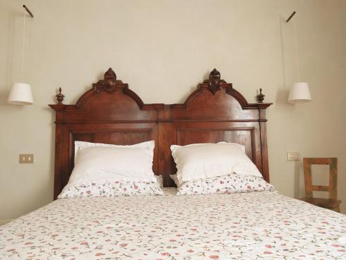 a bed with a wooden headboard and two pillows at Villa Amai in Bene Vagienna