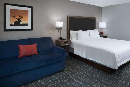 a hotel room with a bed and a blue couch at Hampton Inn North Sioux City in North Sioux City