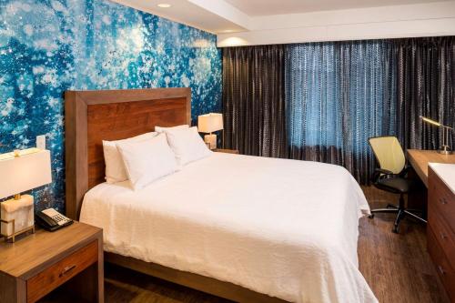 ein Hotelzimmer mit einem Bett und einem Schreibtisch mit einem Schreibtisch in der Unterkunft Hilton Garden Inn Sioux Falls Downtown in Sioux Falls