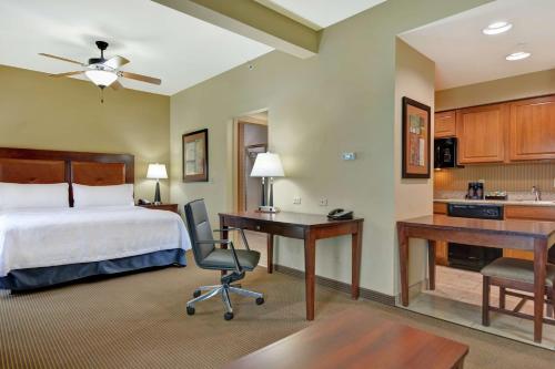 ein Hotelzimmer mit einem Bett, einem Schreibtisch und einer Küche in der Unterkunft Homewood Suites by Hilton Fayetteville in Fayetteville