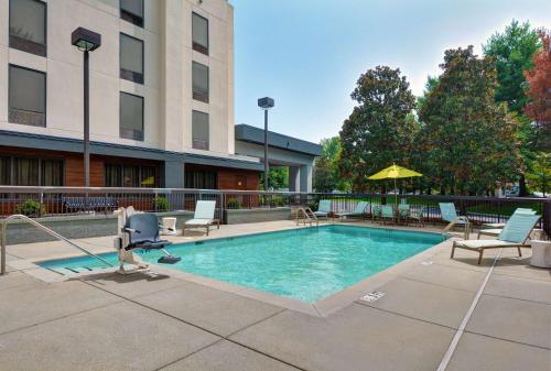 a swimming pool in a courtyard with chairs and an umbrella at Hampton Inn Gallatin in Gallatin