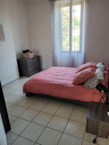 um quarto com uma cama com um edredão vermelho e uma janela em Appartement Le Cricoune em Port-Saint-Louis-du-Rhône