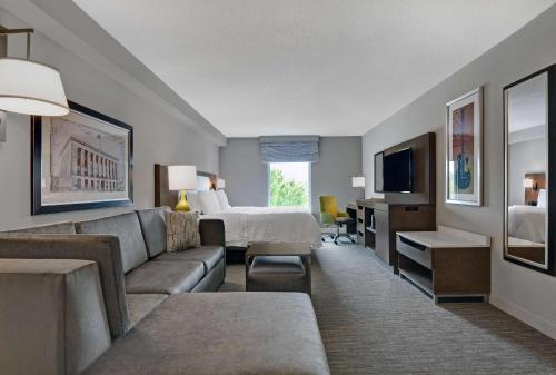 Habitación de hotel con sofá, cama y TV en Hampton Inn Gallatin en Gallatin