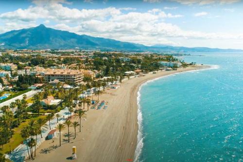 una vista aerea di una spiaggia con palme e l'oceano di Luminosa casa familiar céntrica a Marbella