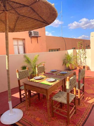 a wooden table with chairs and an umbrella on a patio at Riad Safran Rouge in Marrakech