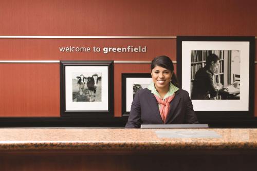 a woman sitting at a counter in a room with pictures at Hampton Inn & Suites Greenfield in Greenfield