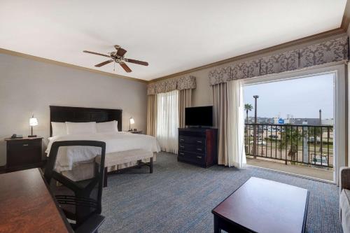 a hotel room with a bed and a large window at Hampton Inn & Suites Galveston in Galveston