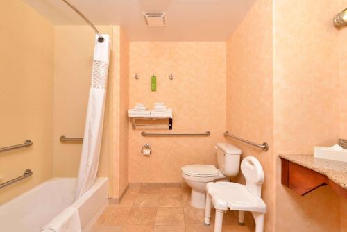 a bathroom with a toilet and a tub and a sink at Hampton Inn Grand Island in Grand Island