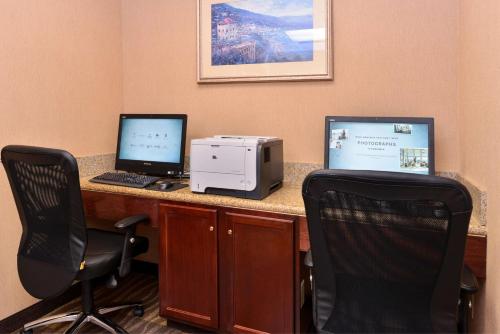 a desk with two computer monitors and a printer at Hampton Inn Grand Island in Grand Island