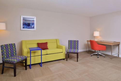 a room with a yellow couch and two chairs and a desk at Hampton Inn Greensboro East / McLeansville in McLeansville