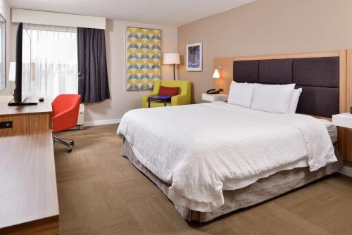 een hotelkamer met een groot bed en 2 stoelen bij Hampton Inn Greensboro East / McLeansville in McLeansville